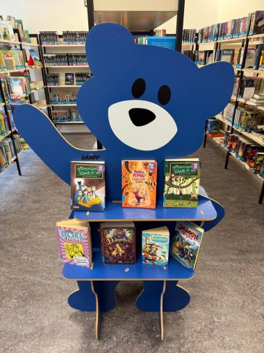 Bild zeigt blauen Aufsteller in Form eines Teddybären im Innenbereich der Stadtbücherei