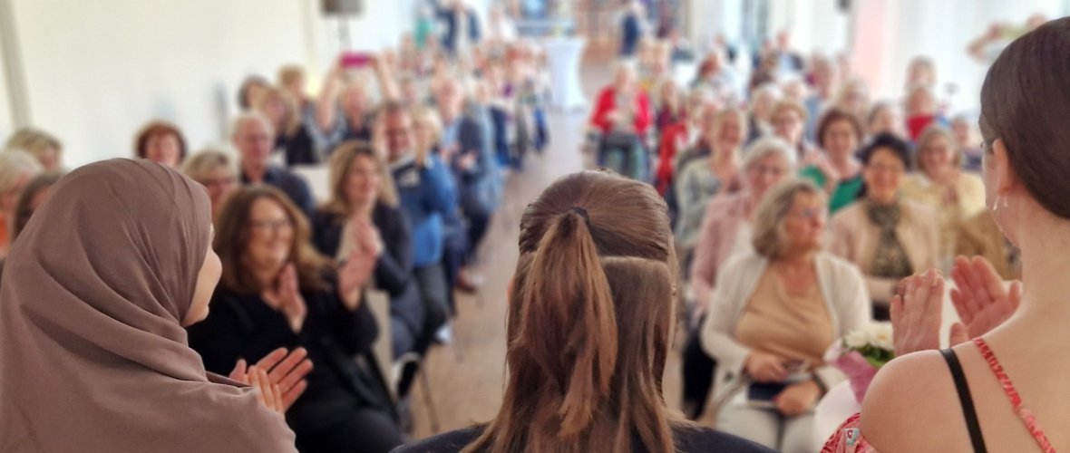 Das Bild zeigt ein applaudierendes Publikum bei einer Veranstaltung in der Bildungswerkstatt von Schloss Eulenbroich.