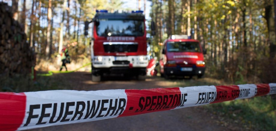 Das Bild zeigt eine Feuerwehrabsperrung im Wald durch einen Waldbrand.