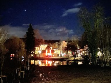 Ansicht durch das Landschaftsfenster auf das beleuchtete Schloss Eulenbroich bei nächtlicher Kulisse.