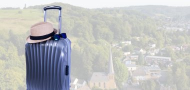 Symbolbild Reisen nach Rösrath Das Bild zeigt einen Reisekoffer vor Rösrather Kulisse.