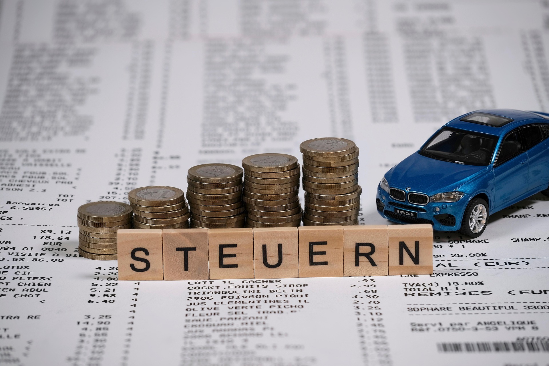 Das Bild zeigt mehrere Stapeln von Münzen. Davor steht der Schriftzug Steuern.