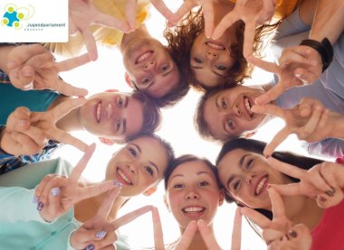 Das Bild zeigt eine Gruppe Jugendlicher, die ihre Köpfe zusammenstecken.