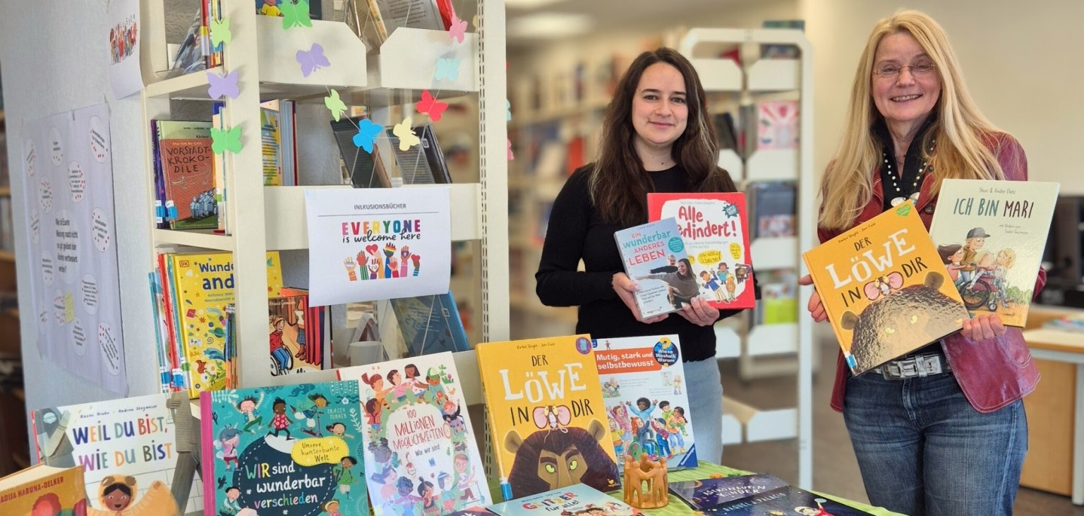 Das Bild zeigt Büchereileiterin Carolyn Bauke und Inklusionsbeauftragte Elke Günzel in der Stadtbücherei.