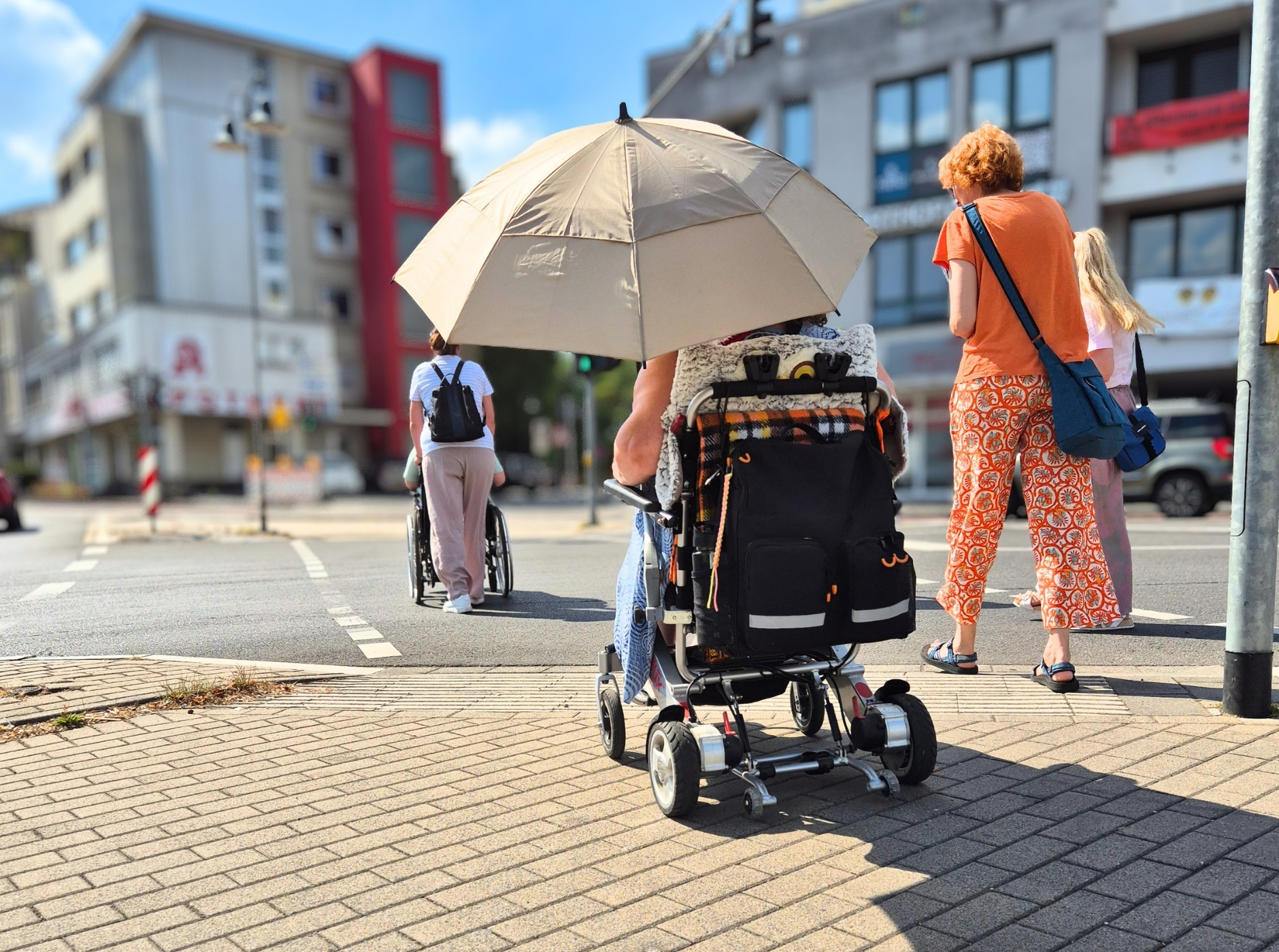 Inklusiver Stadtspaziergang Das Bild zeigt Rollstuhlfahrer beim Überqueren der Kreuzung am Sülztalplatz im Rahmen eines inklusiven Stadtspaziergangs.