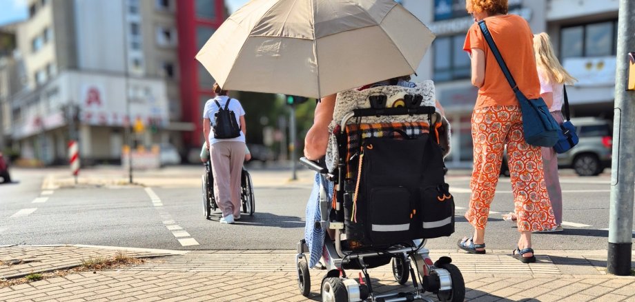 Inklusiver Stadtspaziergang Das Bild zeigt Rollstuhlfahrer beim Überqueren der Kreuzung am Sülztalplatz im Rahmen eines inklusiven Stadtspaziergangs.