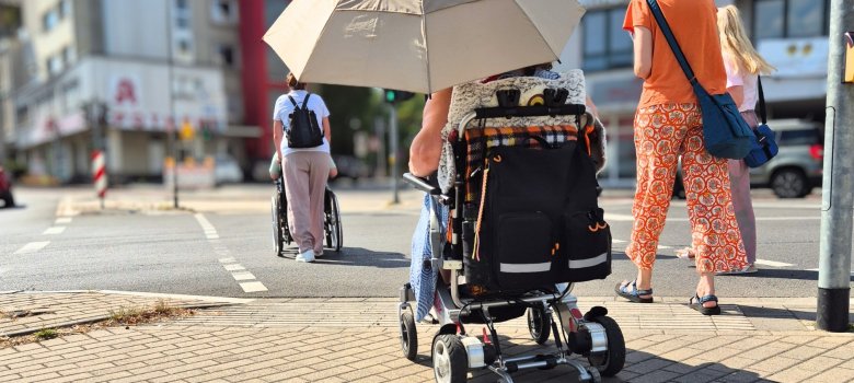 Das Bild zeigt Rollstuhlfahrer beim Überqueren der Kreuzung am Sülztalplatz im Rahmen eines inklusiven Stadtspaziergangs.