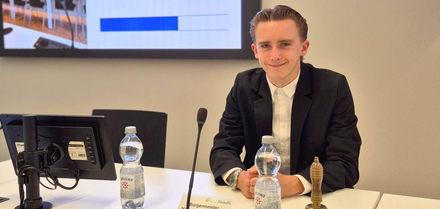 Praktikant Tim Weiß im Ratssaal Das Bild zeigt Praktikant Tim Weiß auf der Sitzungsbank im Ratssaal.