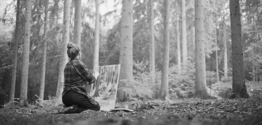 Das Bild zeigt Lukrezia Krämer im Rösrather Wald mit einer Staffelei beim Malen eines Bildes.