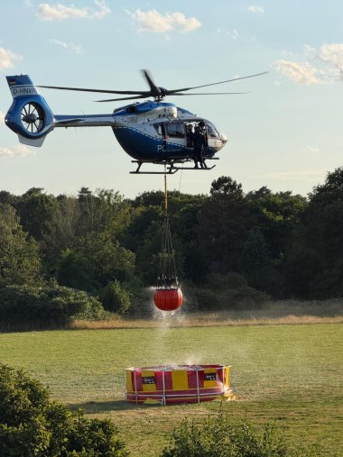 Das Bild zeigt einen Löschhubschrauber, der Wasser aufnimmt.