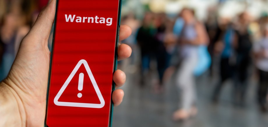 Das Bild zeigt ein Smartphone, auf dessen Display eine Warnung mit der Aufschrift "Warnung" geschrieben steht.