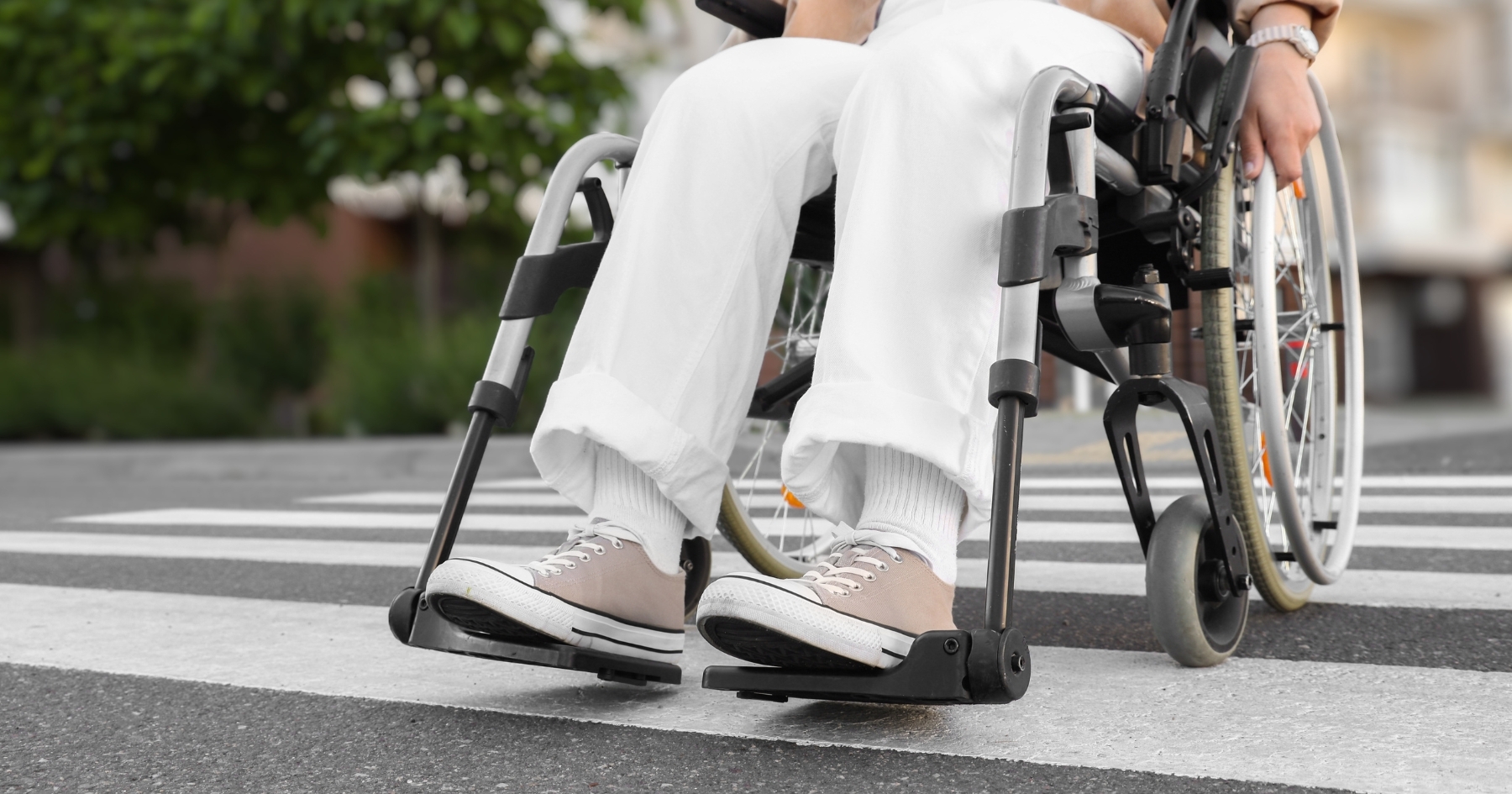 Symbolbild Rollstuhl Das Bild zeigt eine Person im Rollstuhl beim Überqueren eines Zebrastreifens.