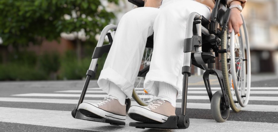 Symbolbild Rollstuhl Das Bild zeigt eine Person im Rollstuhl beim Überqueren eines Zebrastreifens.