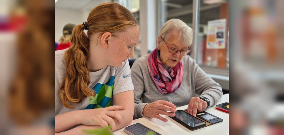 Medienscouts in Aktion Das Bild zeigt die Unterstützung einer Seniorin durch einen Medienscout bei Fragen zu ihrem Smartphone