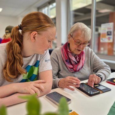Medienscouts in Aktion Das Bild zeigt die Unterstützung einer Seniorin durch einen Medienscout bei Fragen zu ihrem Smartphone
