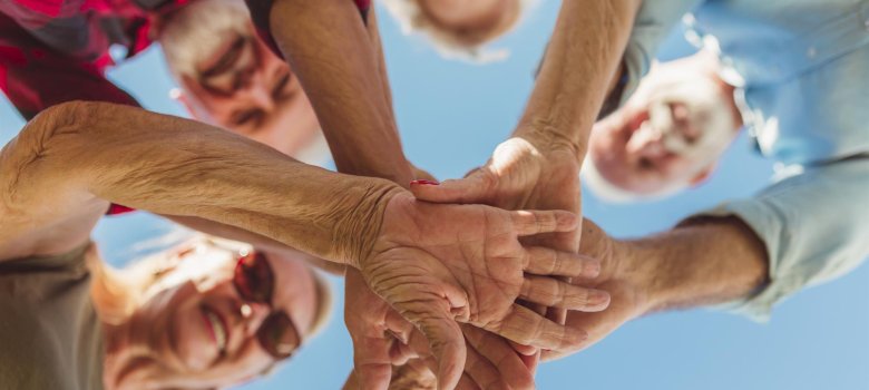 Senioren überkreuzen ihre Hände als Symbol für ein Miteinander.