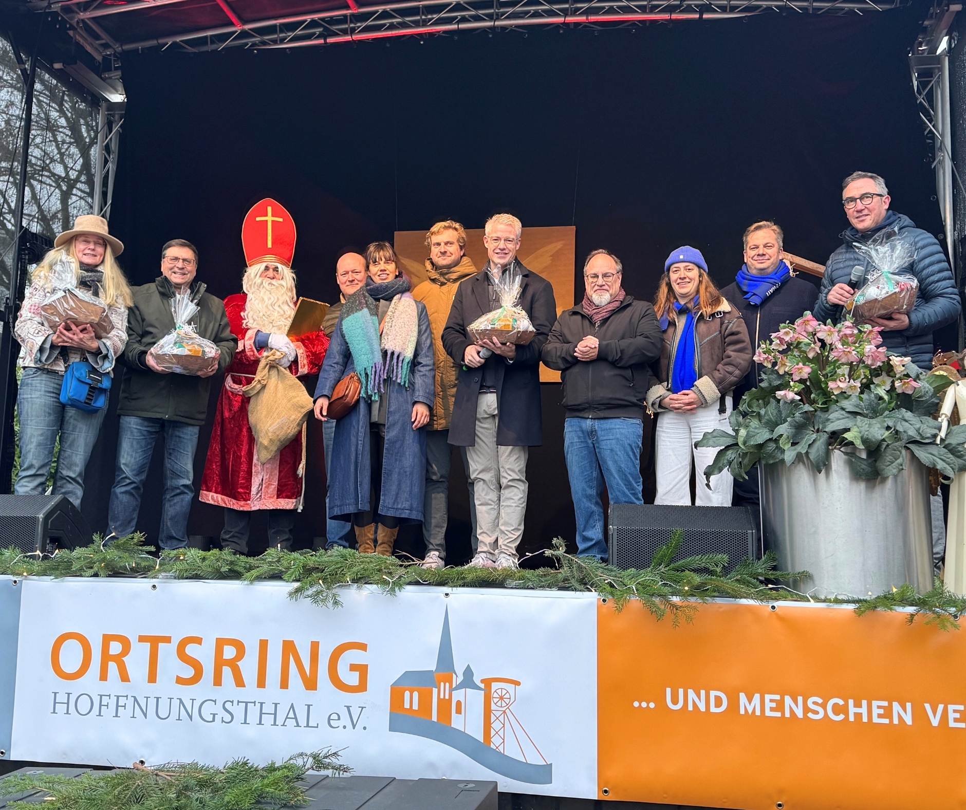 Bürgermeister Yannick Steinbach begrüßt gemeinsam mit seinem belgischen Amtskollegen Peter Roose und weiteren Gästen aus Veurne die Besucherinnen und Besucher des Hoffnungsthaler Weihnachtsmarktes.
