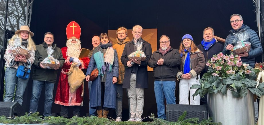Bürgermeister Yannick Steinbach begrüßt gemeinsam mit seinem belgischen Amtskollegen Peter Roose und weiteren Gästen aus Veurne die Besucherinnen und Besucher des Hoffnungsthaler Weihnachtsmarktes.