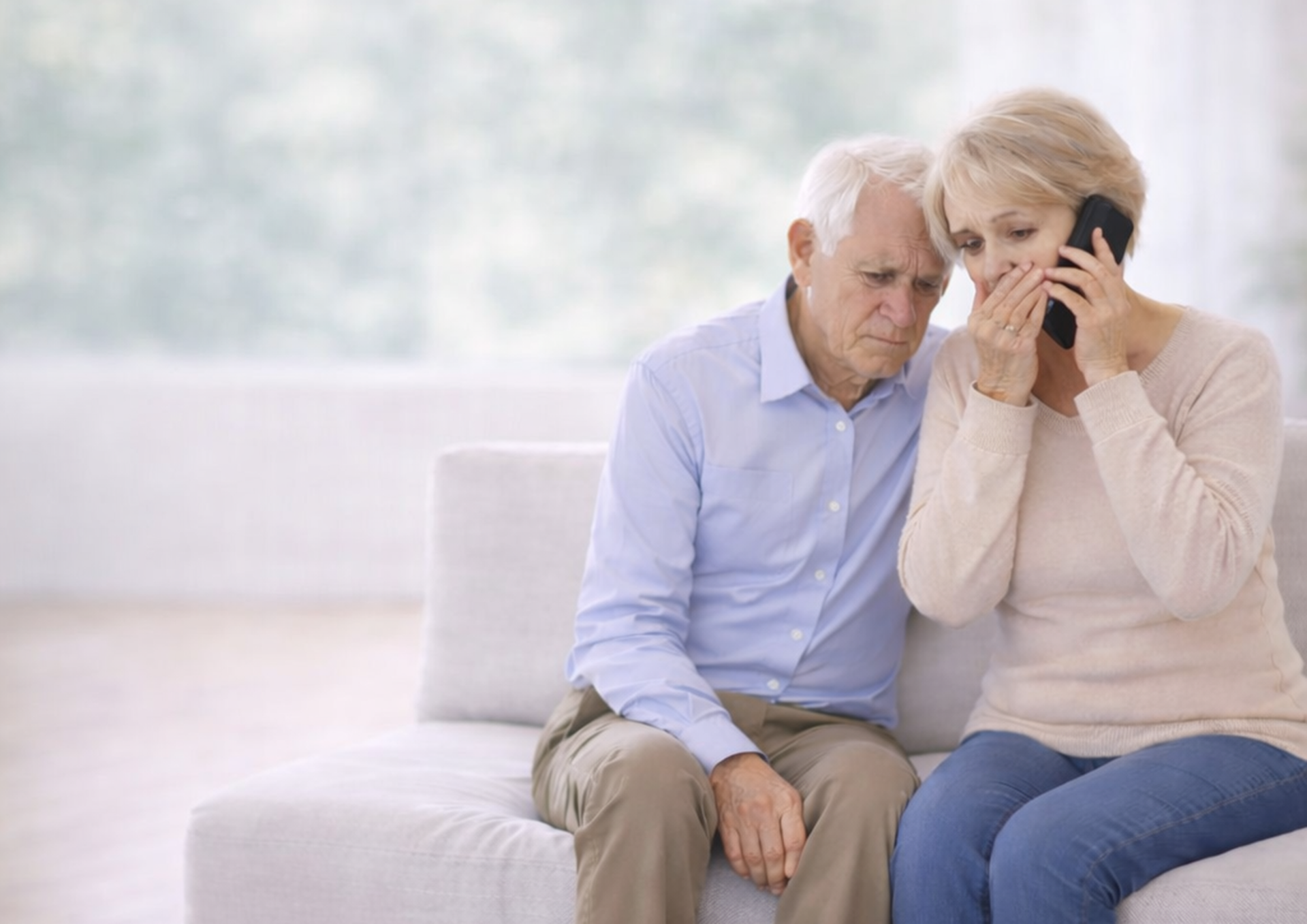 Das Bild zeigt ein besorgtes Seniorenpaar am Telefon.